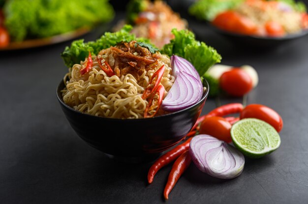 黒いセメント表面に食材を入れたボウルでスパイシーな麺