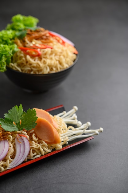 Noodles spicy in Wooden tray with ingredients on black cement surface.