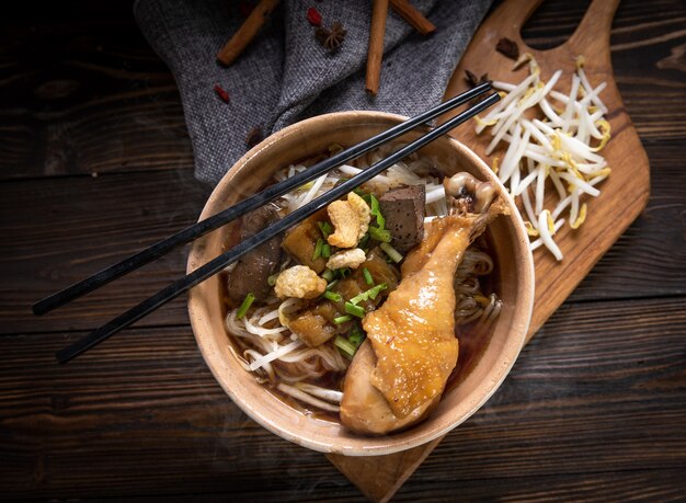 Noodles with chicken leg and chicken fillet, blood with soup Thai style and vegetable. Boat Noodles. Selective focus. Top view