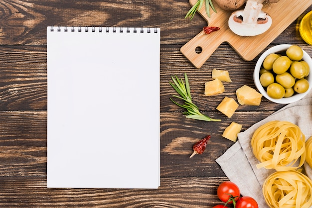 Free photo noodles with olives and vegetables beside notebook