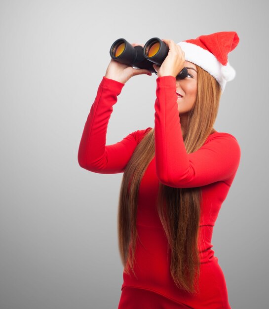 Nosy young woman using binoculars