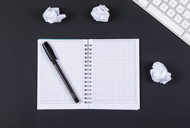 Note taking concept with notebook, pen, crushed paper, keyboard on black background top view. horizontal image