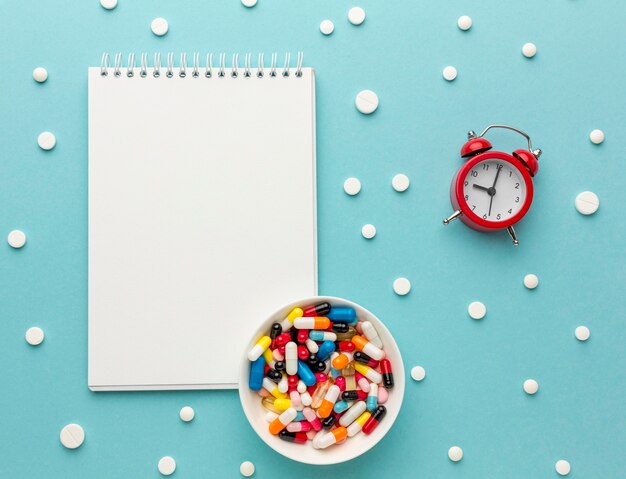 Notebook beside pills and clock