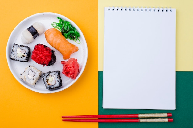 Notebook beside plate with sushi