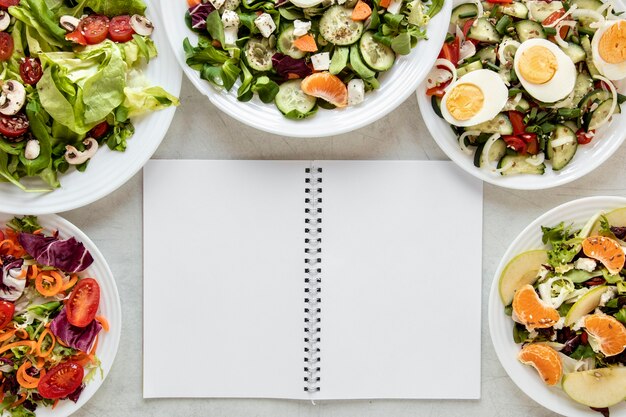 Notebook beside plates with salad