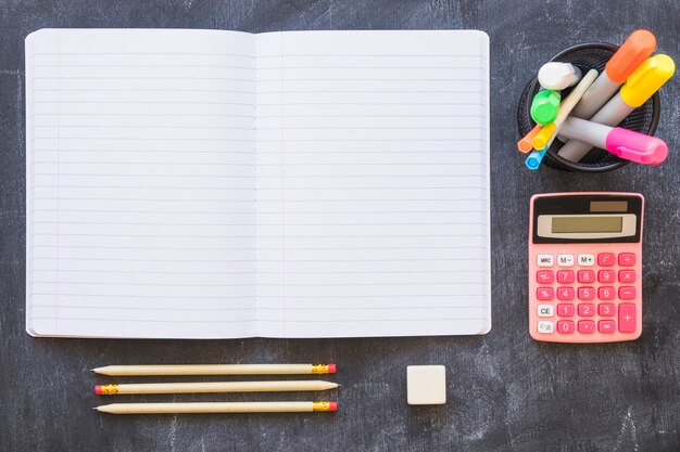 Notebook calculator and stationery on blackboard