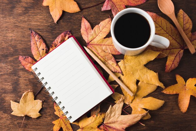 Блокнот и чашка кофе на фоне осенних листьев