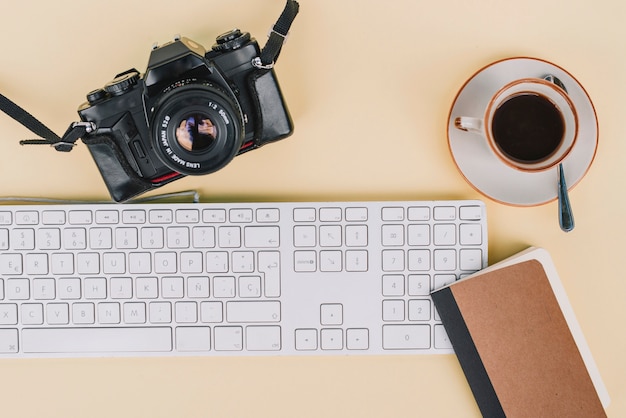 Ноутбук и кофе рядом с камерой и клавиатурой