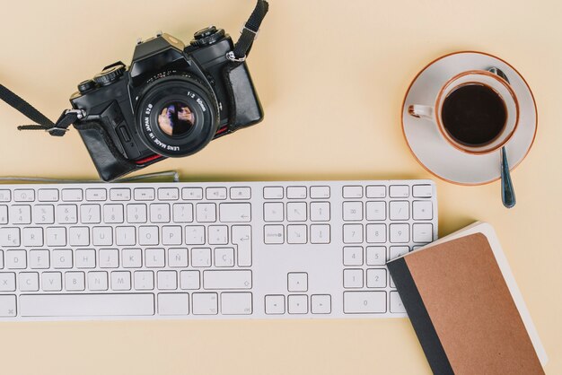 Ноутбук и кофе рядом с камерой и клавиатурой