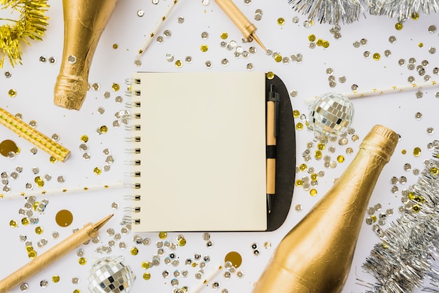 Foto gratuita notebook tra confetti e bottiglie di bevanda