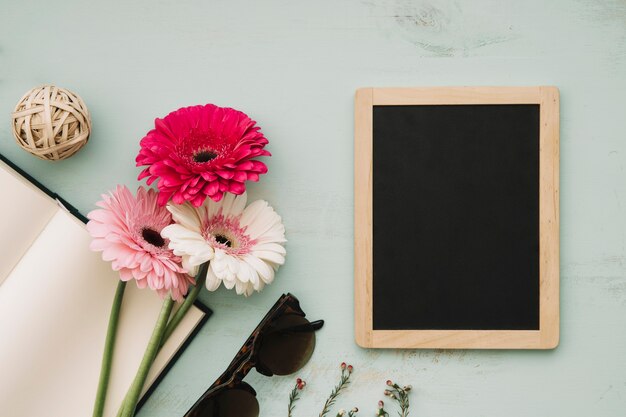 Notebook and flowers near blackboard