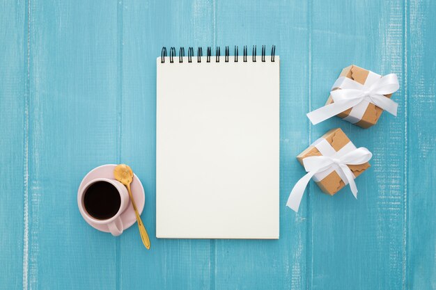 Notebook and gift boxes with coffee on a blue wooden 