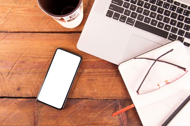 Notebook and glasses near gadgets and mug