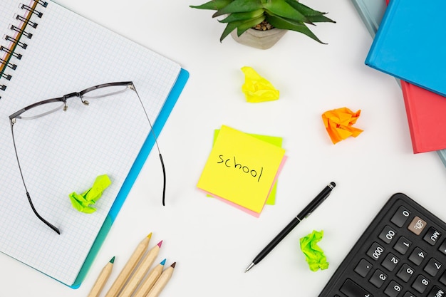 Free photo notebook glasses and paper reminders with the word school on a white background