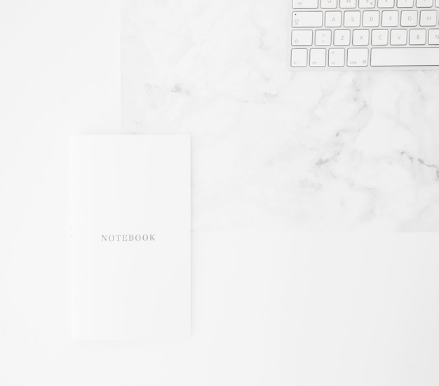 Notebook and keyboard on desk against white backdrop