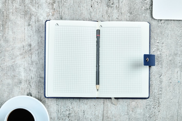 Notebook, laptop and a cup of tea on wooden desk.