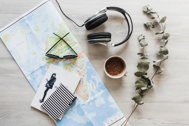 Notebook, map, coffee and headphone on the wooden desk