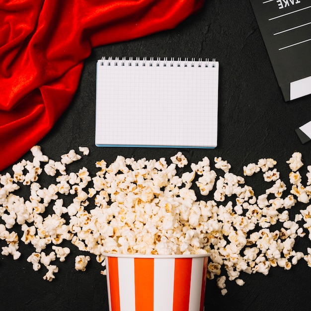 Foto gratuita taccuino vicino a ciak e popcorn