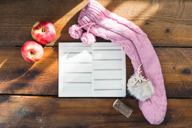 Notebook near knitted sock and apples