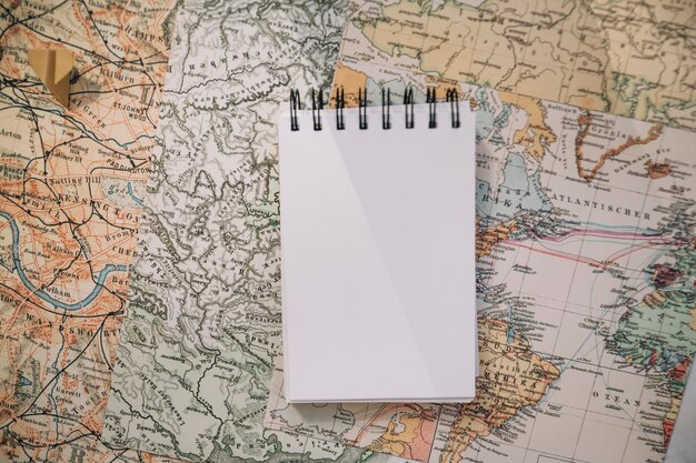 Notebook and paper plane on map