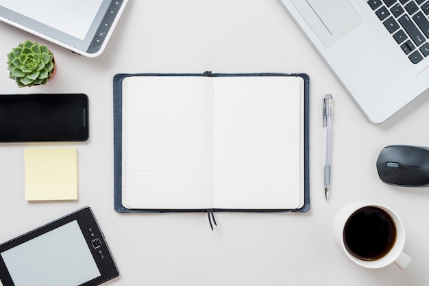 Notebook and pen near electronic devices