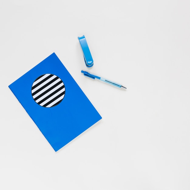 Notebook; pen and stapler on white background