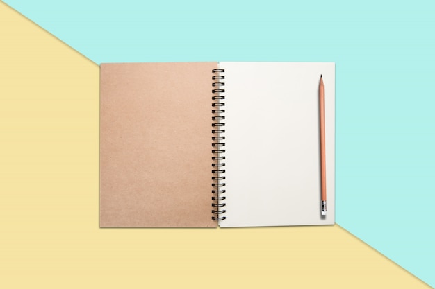 Notebook and pencil on colored background