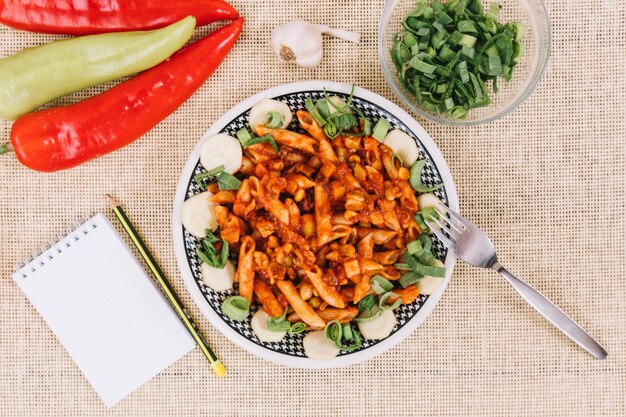 Notebook and pepper near pasta