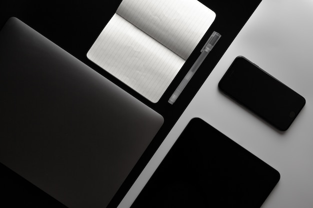 Notebook, telefono e tablet sulla scrivania in bianco e nero
