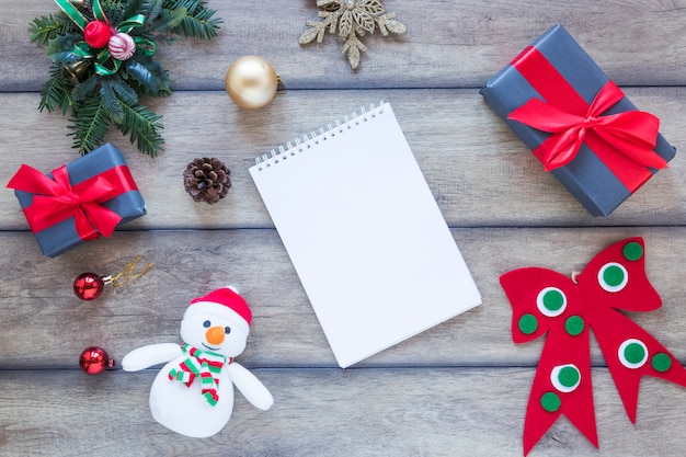 Free photo notebook between present boxes and christmas decorations