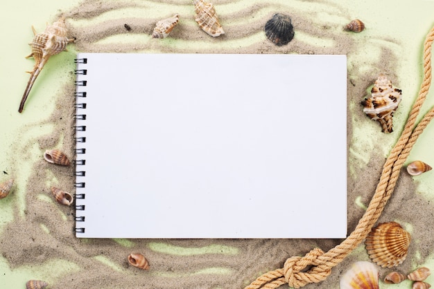 Notebook on sand with nautical rope