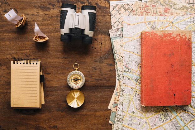 Notebook and tourist stuff near book and maps