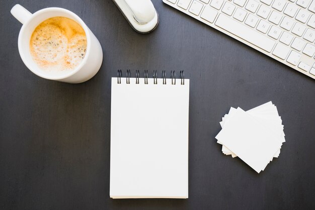 Notebook and visiting cards with coffe mug and keyboard