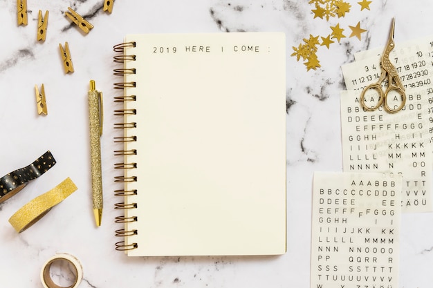 Foto gratuita notebook con 2019 qui vengo iscrizione vicino serie di articoli di cancelleria