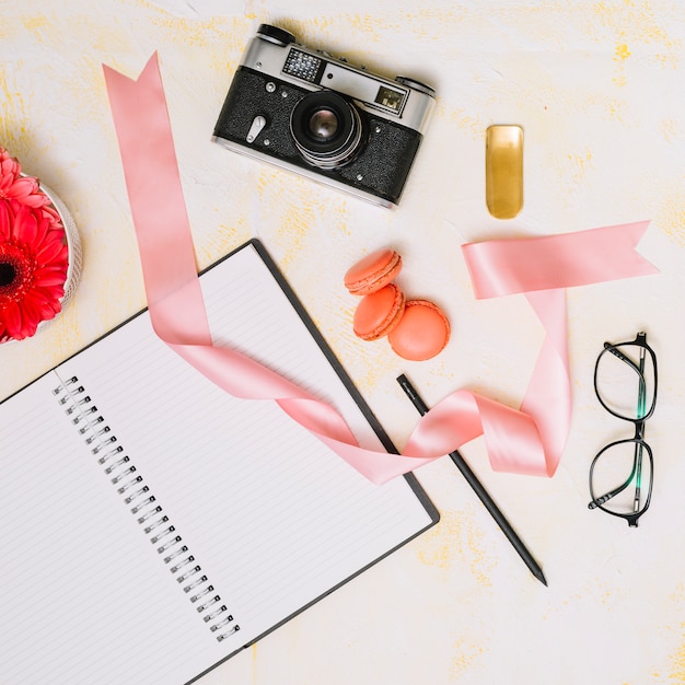 Free photo notebook with camera and ribbon on light table