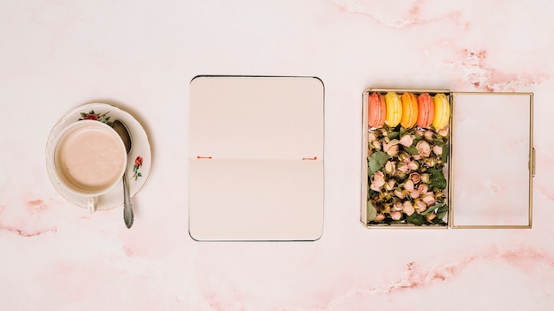 Free photo notebook with coffee cup and box with flowers on table