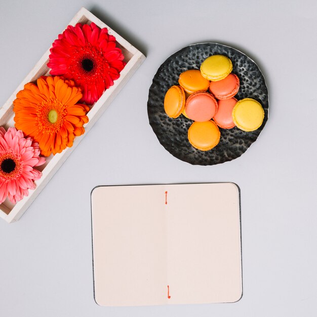 Notebook with cookies and bright flowers on table