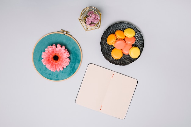 Notebook with cookies and pink flower on table