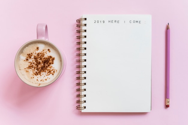 Notebook with inscription near pencil and cup of drink 
