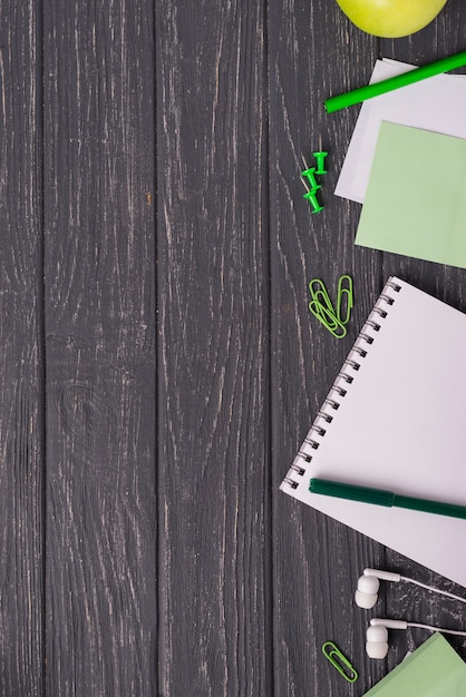 notebook with paper clips and headphones on wooden desk