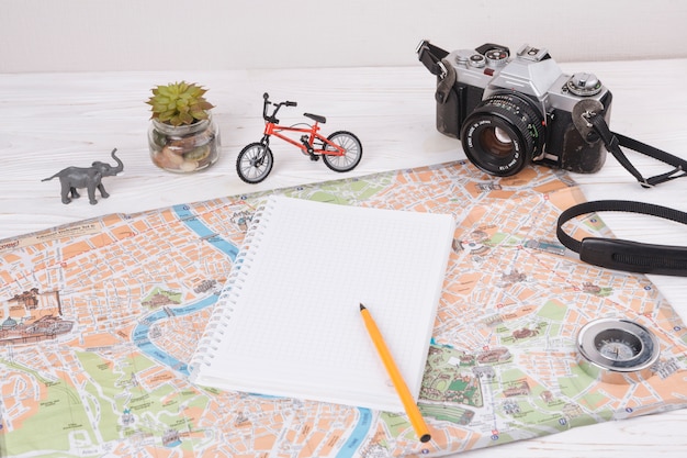 おもちゃの動物、カメラ、自転車の近くの地図の上にペンでノート