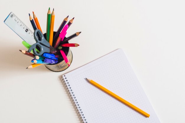 Ноутбук с карандашом возле письменных принадлежностей
