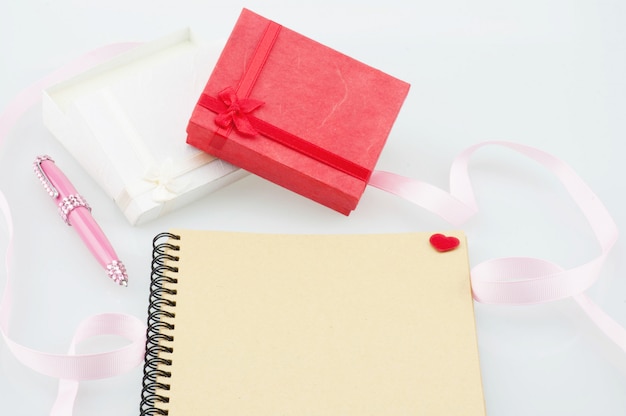 Notebook with pink pen and present boxes 