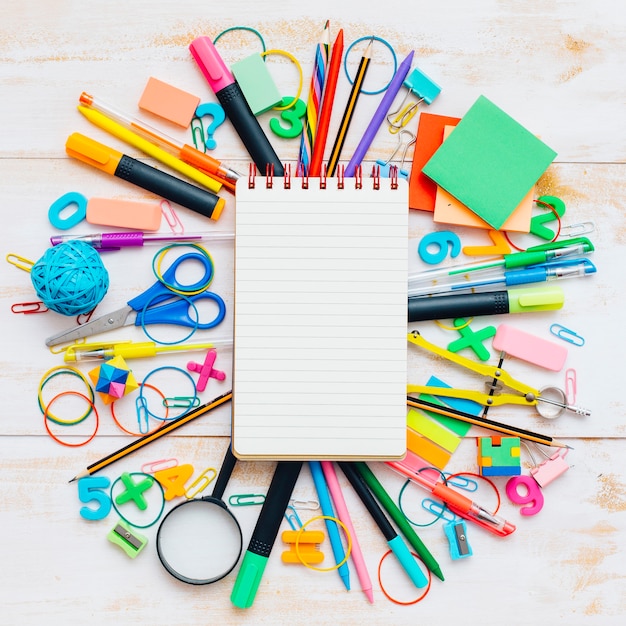 Notebook with school objects in wooden background.