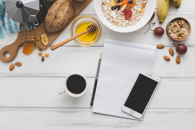 Notebook with smartphone near breakfast food