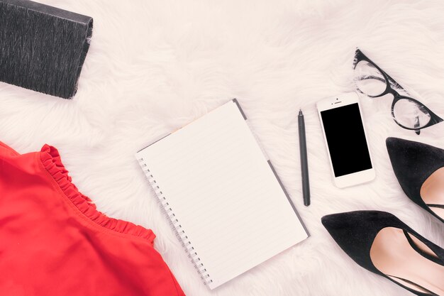 Notebook with smartphone and skirt on blanket 