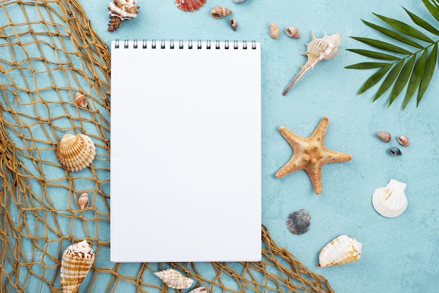 Notebook with starfish beside and shells