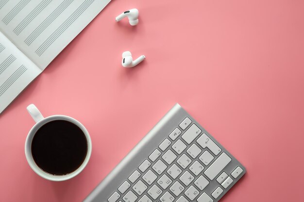 Notebook for writing notes and a cup of coffee on a pink background flat lay