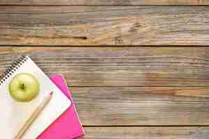 Free photo notebooks and an apple on a wooden background top view