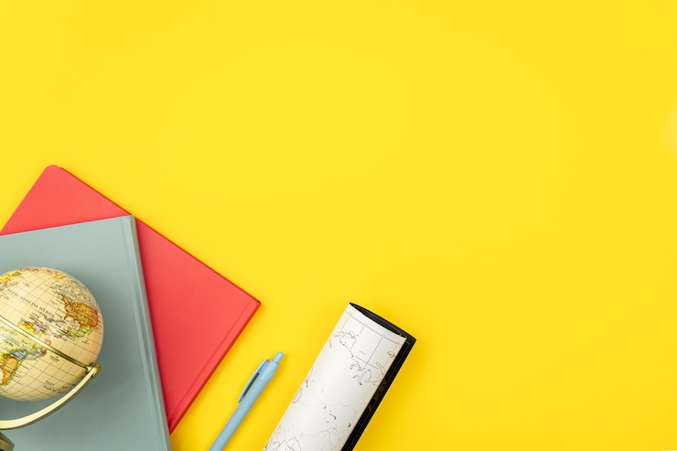 Free Photo notebooks globe and map on a yellow background flat lay